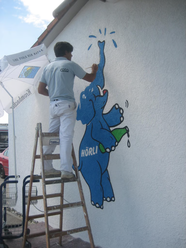 Handwerker malt blaues Elefanten-Wandbild HÖRLI – kreative Wandgestaltung von Malerei Cota